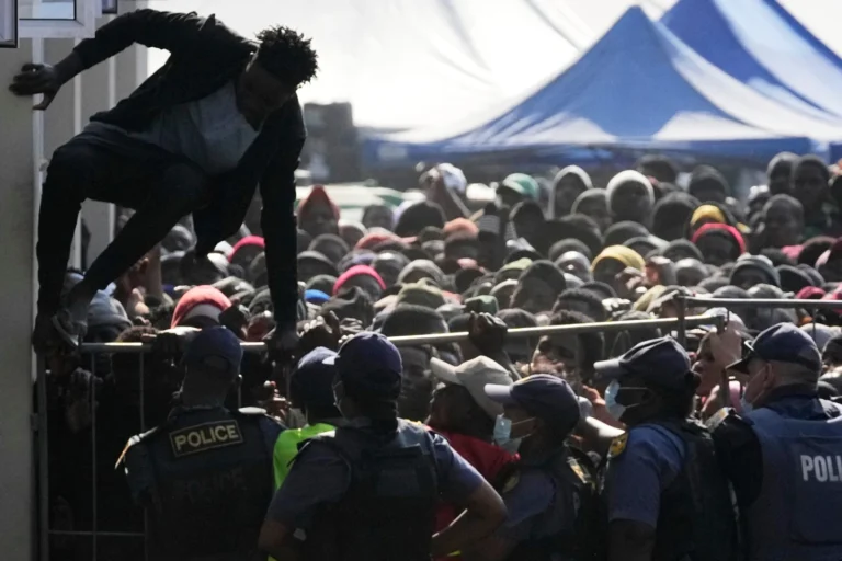 (A Malawian migrant jumps over a barricade as the police officer manage the queue for their deportation at a temporary centre, in Durban, South Africa, Thursday, June 18, 2026. (AP File Photo: Themba Hadebe)