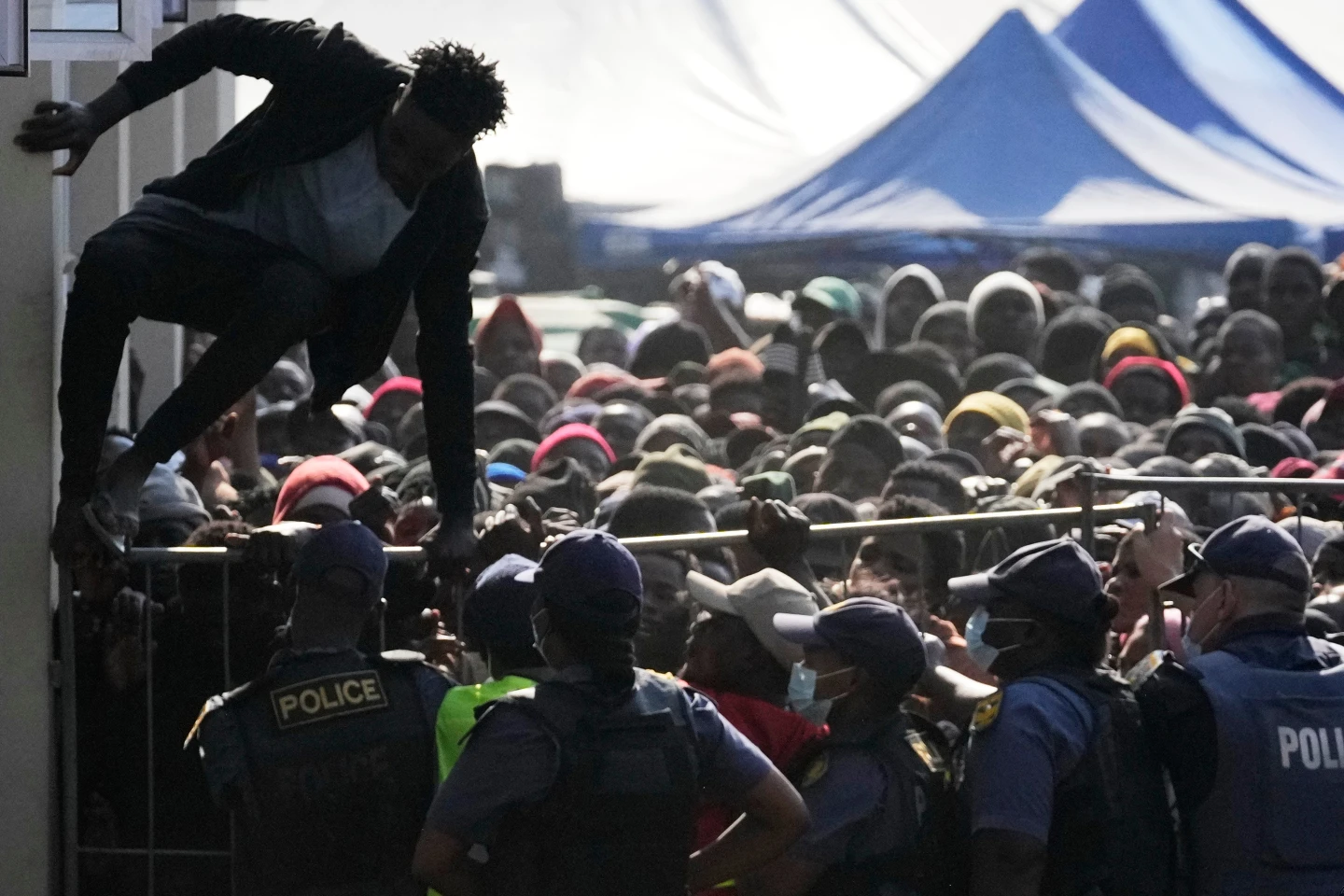 (A Malawian migrant jumps over a barricade as the police officer manage the queue for their deportation at a temporary centre, in Durban, South Africa, Thursday, June 18, 2026. (AP File Photo: Themba Hadebe)