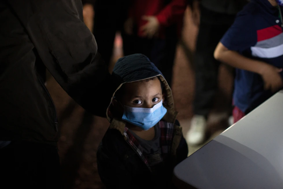(An unaccompanied minor looks up as he waits to answer questions from a U.S. Border Patrol agent at an intake site after he was smuggled on an inflatable raft across the Rio Grande River, March 24, 2021, in Roma, Texas. (AP File Photo: Dario Lopez-Mills)